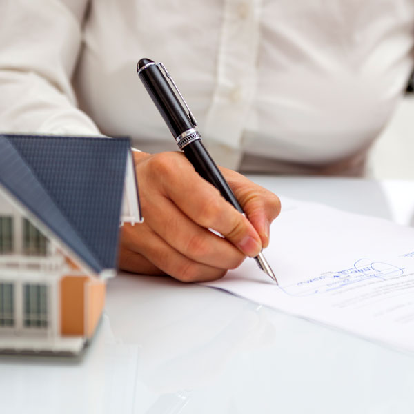 woman singing document next to small model home